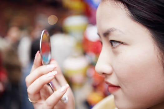 Close-up of a young woman looking into a vanity mirror