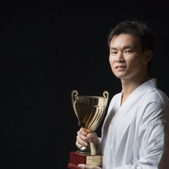 Portrait of a young man holding a trophy