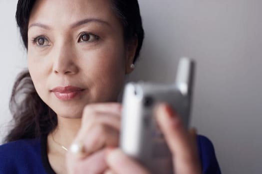 Close-up of a mature woman holding a mobile phone thinking