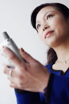 Low angle view of a mature woman holding a mobile phone thinking