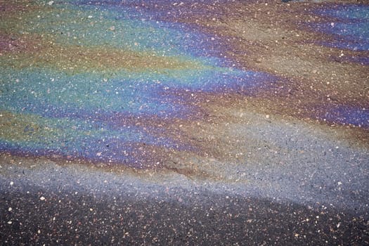 A bright oil slick with a whole range of bright colors on the asphalt surface