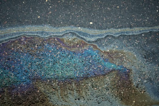 A colored gasoline slick on a wet asphalt road highlighting the risks associated with pollution