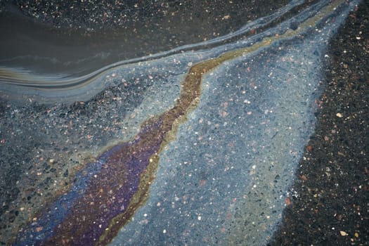 A puddle of gasoline on a rainy asphalt surface, highlighting the danger of environmental pollution