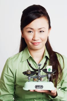 Portrait of a young woman holding a weighing scale and smiling