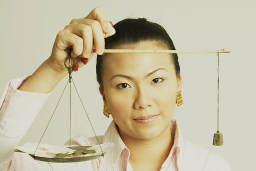 Portrait of a businesswoman weighing paper currency with coins on a weighing scale