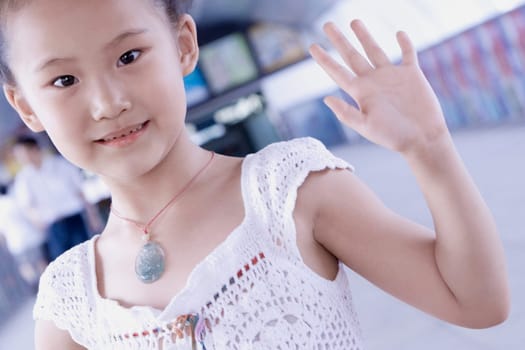 Portrait of a girl waving her hand in a corridor