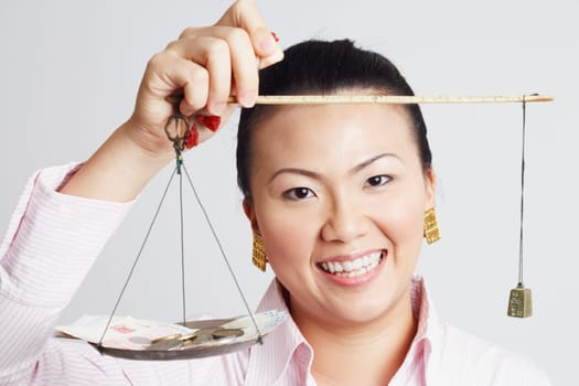 Portrait of a businesswoman weighing paper currency with coins on a weighing scale and smiling