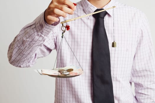 Mid section view of a businessman weighing paper currency with coins on a weighing scale