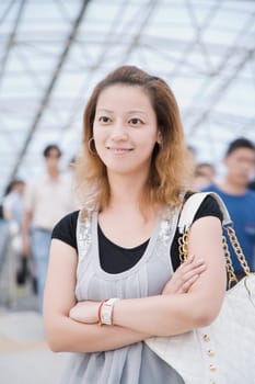 Young woman standing in a corridor with her arms crossed and smiling