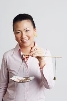 Portrait of a businesswoman weighing paper currency with coins on a weighing scale and smiling