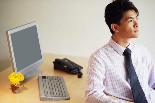 Close-up of a young man sitting in an office and thinking