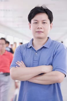 Portrait of a mid adult man standing with his arms crossed in a corridor