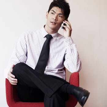 Businessman sitting in an armchair and talking on a mobile phone