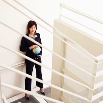 Portrait of a businesswoman holding a globe and posing