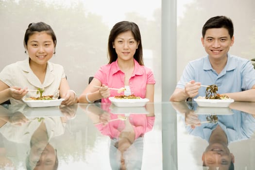 Portrait of three office workers having lunch and smiling