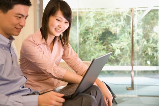 Young man sitting beside a young woman with a laptop