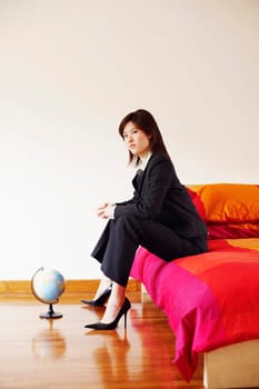 Portrait of a businesswoman sitting on the bed with her hands clasped