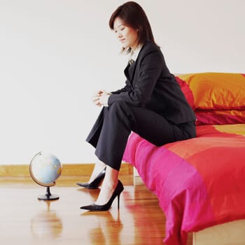 Side profile of a businesswoman sitting on the bed and looking at a globe
