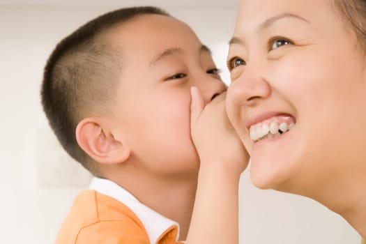 Close-up of a boy whispering to his mother