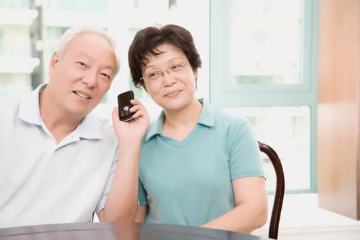Close-up of a mature couple smiling and holding a mobile phone