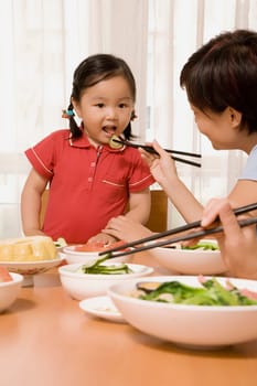 Side profile of a mid adult woman feeding her daughter