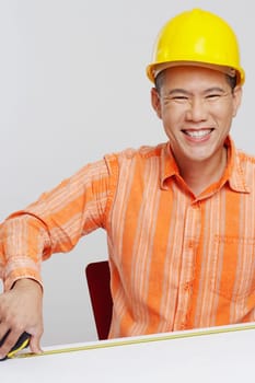 Portrait of a male architect measuring a desk with a tape measure and smiling