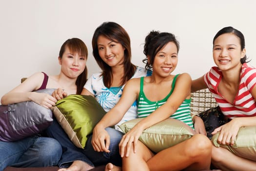 Portrait of four young women sitting on a couch and smiling