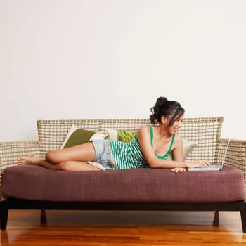 Young woman using a laptop on a couch and smiling