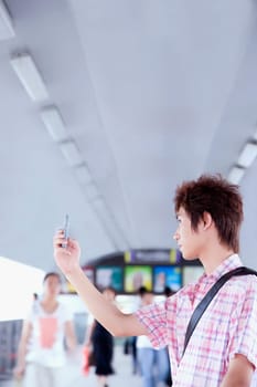 Side profile of a young man taking a picture with his mobile phone