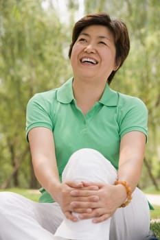 Mature woman sitting in a park and smiling
