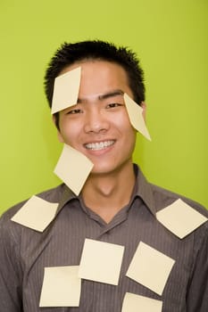 Portrait of a male office worker covered with adhesive notes and smiling