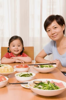 Portrait of a mid adult woman sitting with her daughter at a dining table