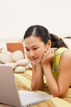 Close-up of a young woman looking at a laptop and thinking