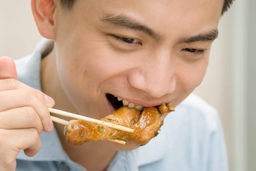 Close-up of a male office worker eating meat with chopsticks