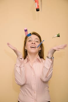 Close-up of a mid adult woman tossing stationery objects and smiling