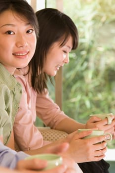Two female office workers holding coffee cups and smiling