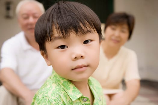 Portrait of a boy with his grandparents sitting behind him