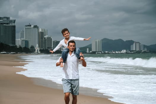 happy father dad with a child son on are walking along the beach by the sea on a summer vacation