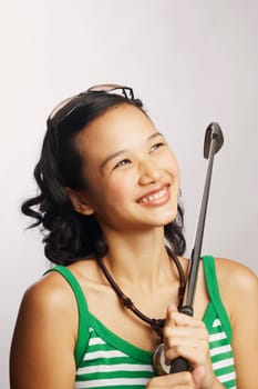 Close-up of a young woman holding a golf club and looking up