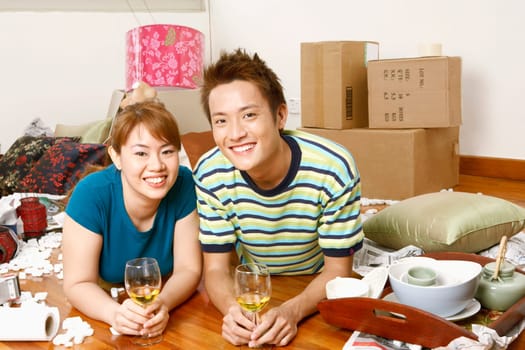 Portrait of a young couple lying on the floor and holding glasses of wine