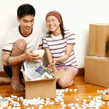Young woman and a mid adult man holding a bowl in a messy room