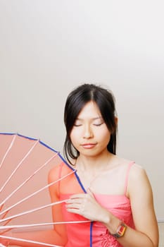 Close-up of a young woman holding a parasol with her eyes closed
