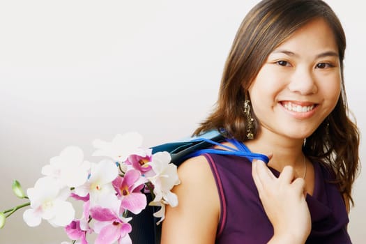 Portrait of a young woman carrying flowers in a shopping bag