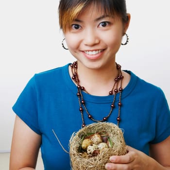 Portrait of a young woman holding eggs in a birdŽs nest and smiling