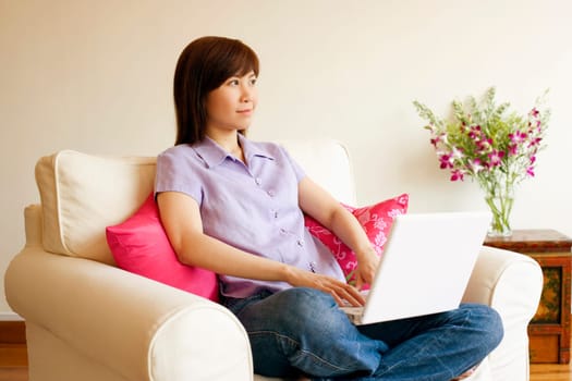 Young woman sitting in an armchair with a laptop