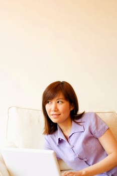 Close-up of a young woman lying on a couch with a laptop
