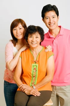 Portrait of a mature woman sitting on a stool with a young couple standing beside her