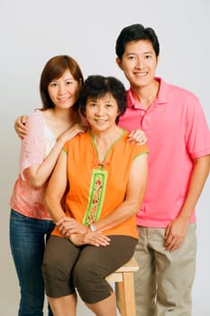 Portrait of a mature woman sitting on a stool and a young couple standing beside her