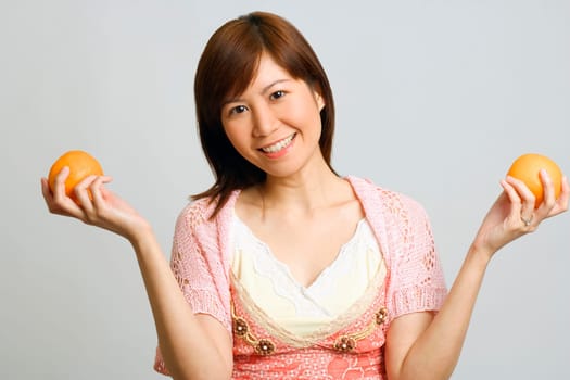 Portrait of a young woman holding oranges
