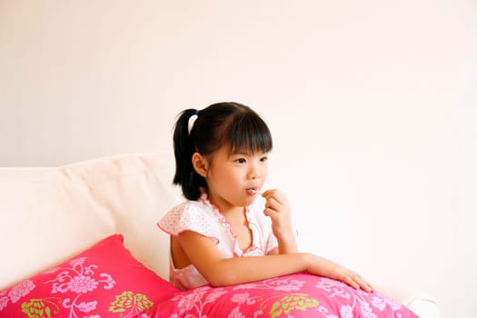 Girl sitting on a couch and eating a lollipop